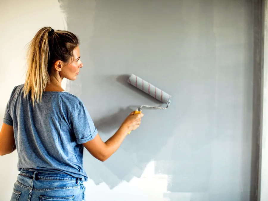 Painter rolling fresh paint onto an interior wall with a roller