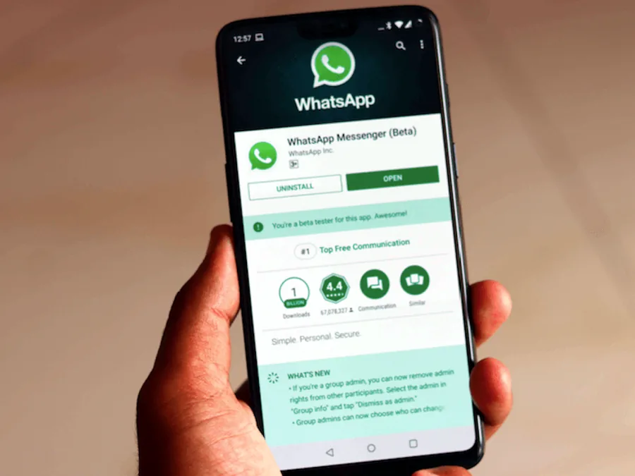 Hand holding a phone with the WhatsApp app open on screen